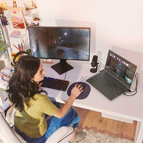 Woman gaming at a desk with dual monitors.